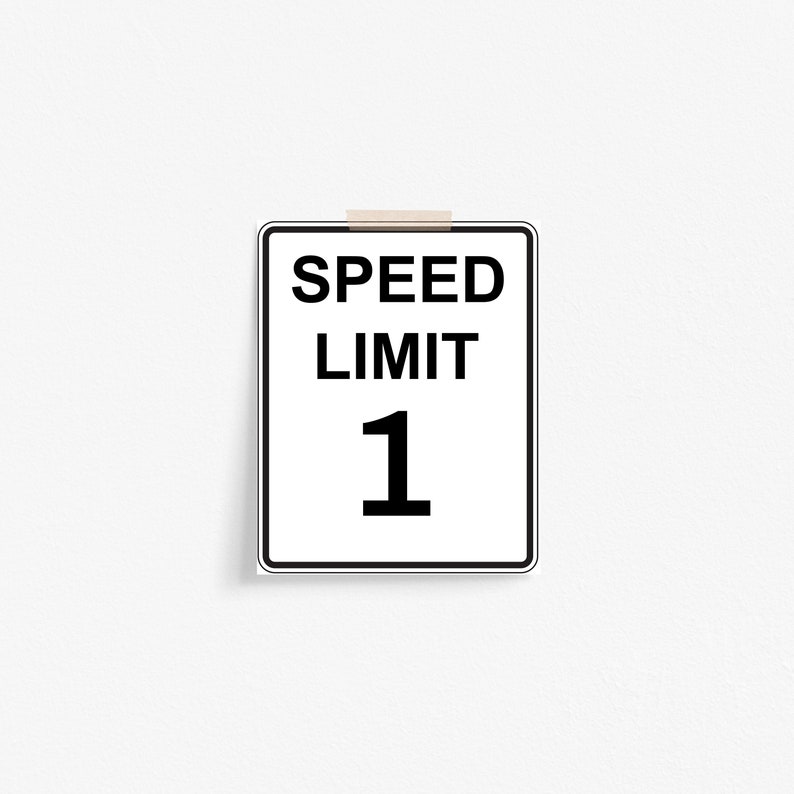 May include: A white speed limit sign with black text and border. The sign reads "SPEED LIMIT 1".