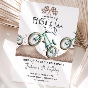 May include: A birthday invitation featuring a watercolor illustration of a green bicycle jumping over a dirt mound. The text "Jackson is Fast & Five" is displayed above the bicycle, with additional text below inviting guests to celebrate Jackson's 5th birthday.