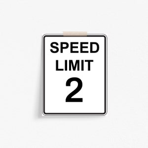 May include: A white and black speed limit sign with the text "SPEED LIMIT 2" on it.