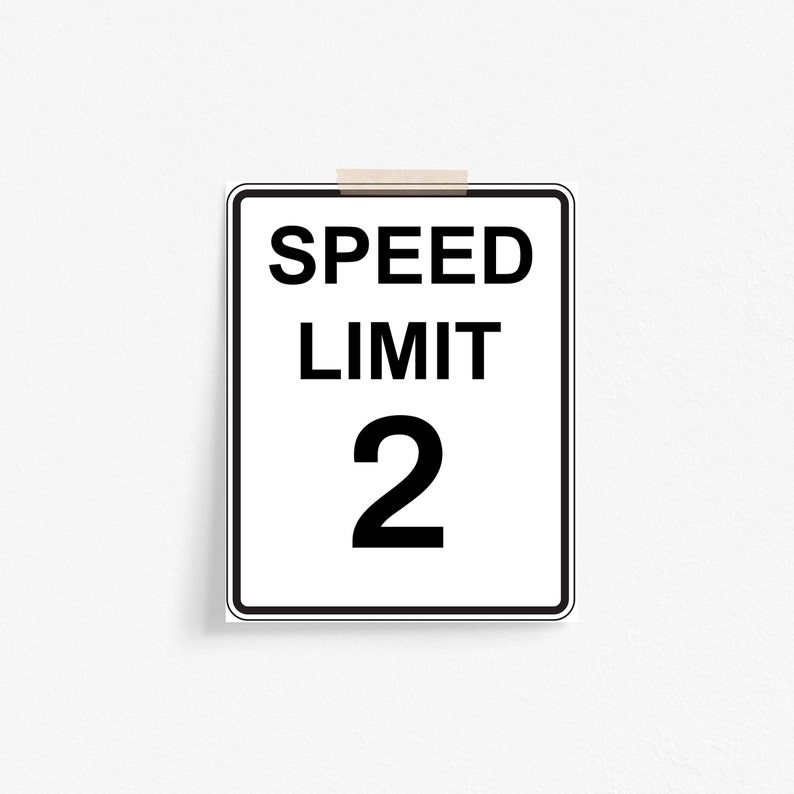 May include: A white and black speed limit sign with the text "SPEED LIMIT 2" on it.