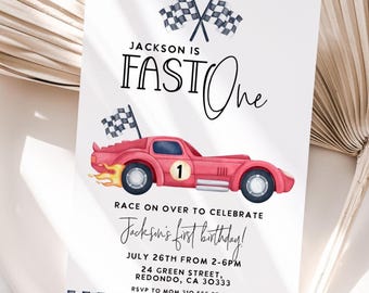 Może przedstawiać: Zaproszenie urodzinowe z ilustracją czerwonego samochodu wyścigowego, szachownicami i napisem "Jackson is FAST One". Zaproszenie zawiera tekst "Race on over to celebrate Jackson's first birthday!"