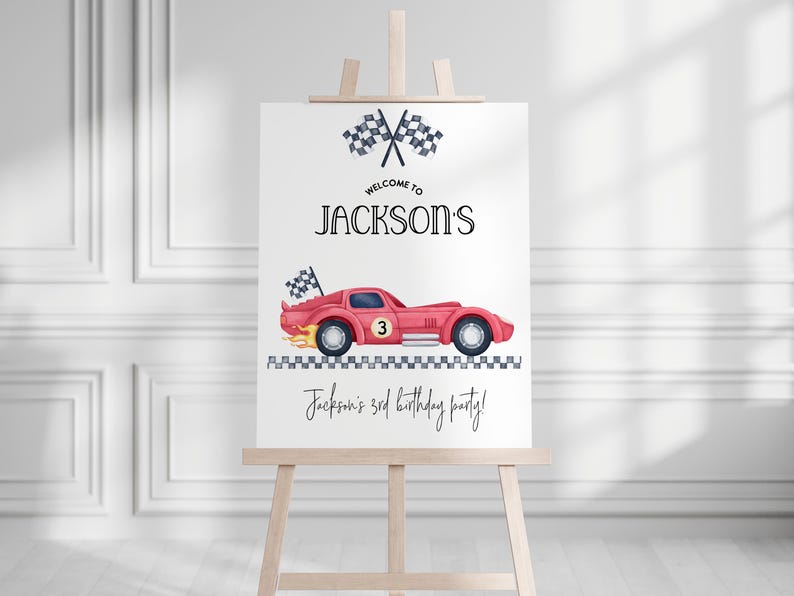 Pu&ograve; includere: Un cartello bianco su un cavalletto di legno presenta un'auto da corsa rossa con il numero 3, bandiere a scacchi e il testo "Welcome to Jackson's" e "Jackson's 3rd birthday party!" in nero.