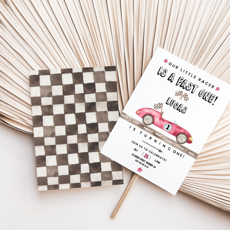 May include: A white invitation with a red race car and checkered flag design. The text reads "Our Little Racer is a Fast One! Lucas is Turning One!" and includes details for a birthday party.