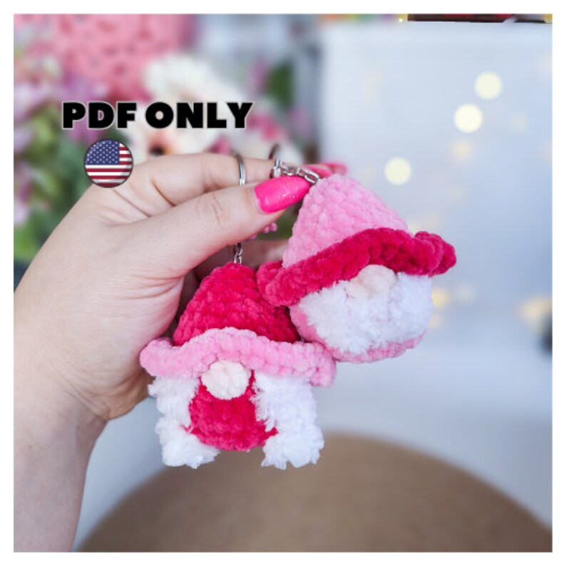 May include: Two pink and white crocheted gnome keychains with white beards and pink hats. The keychains are attached to a silver keyring.