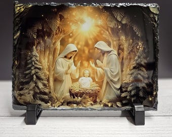 May include: A rectangular stone plaque featuring a religious scene. The image depicts two figures in white robes, with hands raised, looking at a baby in a manger. The background includes trees and a bright light source, with the plaque resting on a black stand.
