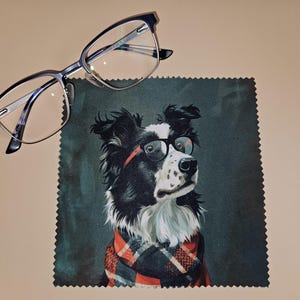 May include: Eyeglasses with a black and silver frame rest above a microfiber cloth featuring a black and white dog wearing glasses and a red and black plaid scarf. The dog is a Border Collie.