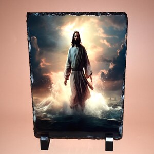 May include: A rectangular slate plaque featuring an image of a figure in flowing robes standing in water, with a bright, cloudy sky in the background. The image is mounted on a black stand.