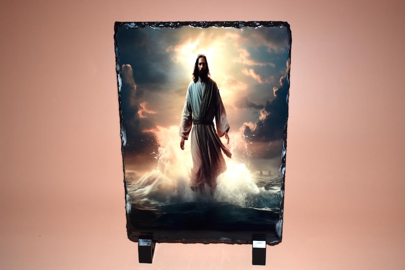 May include: A rectangular slate plaque featuring an image of a figure in flowing robes standing in water, with a bright, cloudy sky in the background. The image is mounted on a black stand.