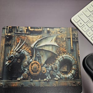Puede incluir: Alfombrilla de ratón con un diseño de dragón steampunk. El dragón está compuesto por engranajes y elementos mecánicos, en tonos bronce, plata y gris. Un teclado blanco y un ratón negro son visibles en el fondo.