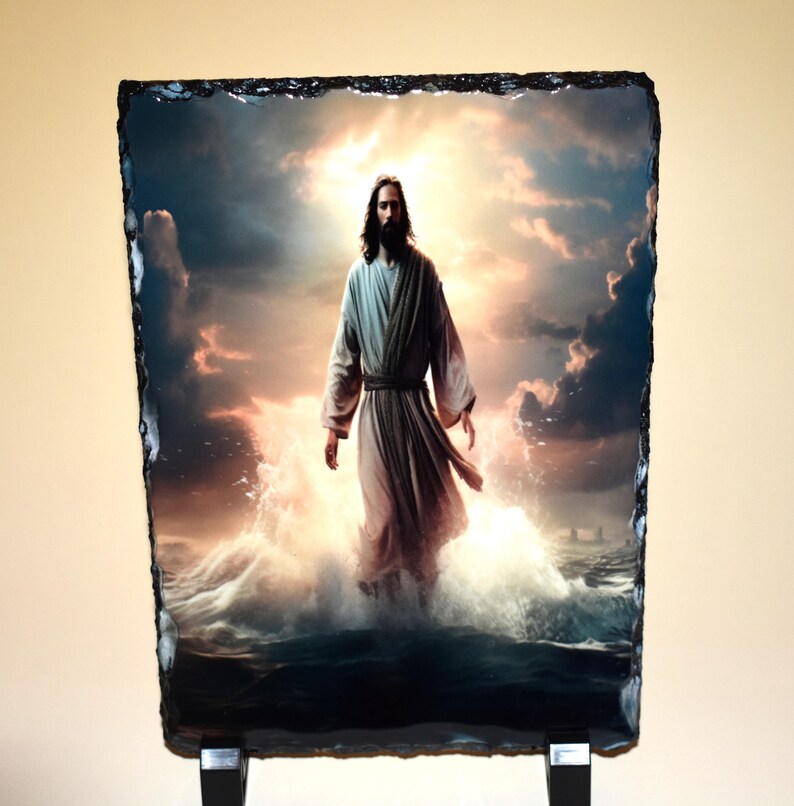 May include: A rectangular slate print depicts a figure in flowing robes walking on water, with a bright, cloudy sky in the background. The image is mounted on a black stand, showcasing a religious theme.