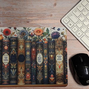 Puede incluir: Alfombrilla de ratón decorativa con una fila de libros de estilo vintage y detalles florales. Los libros tienen diseños ornamentados y títulos como "Pride and Prejudice" y "Romeo and Juliet". Un teclado blanco y un ratón negro están en la imagen.
