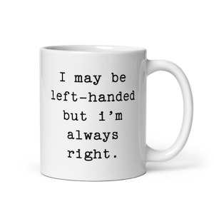 May include: White ceramic coffee mug with black text that reads "I may be left-handed but I'm always right."