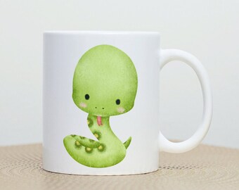 Peut inclure: Une tasse en céramique blanche avec un serpent de dessin animé vert avec une langue rose et des yeux noirs. Le serpent est enroulé sur lui-même avec sa queue dans sa bouche.