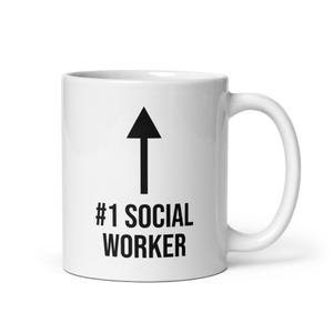 Könnte beinhalten: Weiße Keramik-Kaffeetasse mit einem schwarzen Pfeil, der nach oben zeigt, und dem Text "#1 SOCIAL WORKER", der auf der Vorderseite aufgedruckt ist.