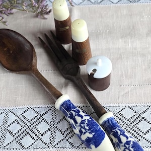 Puede incluir: Una taza de cerámica blanca con un asa negra y el texto "But First, Coffee" en negrita negra. La taza está llena de un líquido oscuro, probablemente café, y se encuentra sobre una superficie clara.