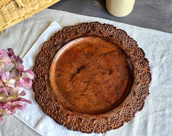 Bandeja redonda de cobre martelado antigo, 30 cm, com relevo floral, para servir ou decorar paredes.