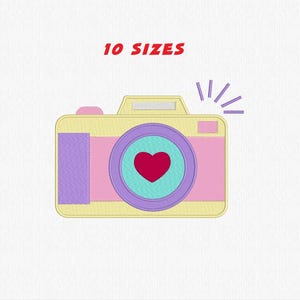 Può includere: Toppa ricamata di una macchina fotografica a cartoni animati in colori pastello. La fotocamera è gialla, rosa e viola, con un cuore rosso al centro dell'obiettivo. Il testo sopra la fotocamera recita "10 SIZES".