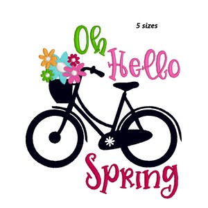 Può includere: Una bicicletta nera con un cestino pieno di fiori colorati. La bicicletta ha una stella bianca sul telaio. Il testo "Oh Hello Spring" è scritto in lettere rosa.