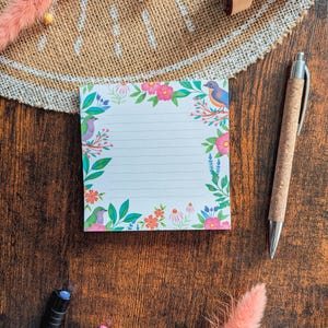 Peut inclure: Un bloc-notes blanc avec une bordure florale et des oiseaux bleus. Le bloc-notes a des pages lignées et est parfait pour noter des notes, des idées ou des listes.