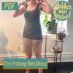 May include: A crochet dress with a net-like pattern in a light green color. The dress has a side slit and is worn by a person standing in front of a window. The text "The Fishing Net Dress" is at the bottom of the image.