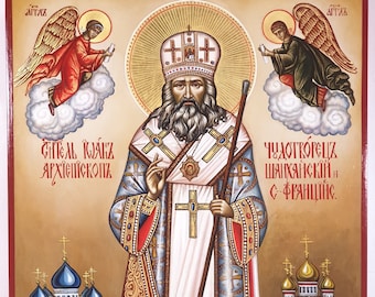 May include: An icon featuring a religious figure in ornate robes, holding a staff, with text in Cyrillic script. Two angels flank the central figure, and two churches are depicted at the bottom. The artwork is framed in red.