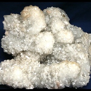 Peut inclure: Gros plan sur un amas de cristaux de quartz blancs et transparents. Les cristaux présentent une surface rugueuse et texturée, avec un aspect scintillant. Certaines zones présentent une couleur beige clair. La forme générale est irrégulière et organique.