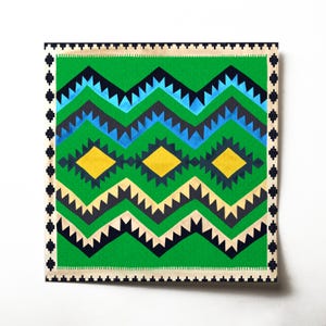 Op de afbeelding: Een geometrisch tapijt met groene, blauwe, gele en zwarte patronen met een witte rand. Het tapijt heeft een zigzagpatroon met ruitvormen.