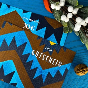 Könnte beinhalten: Ein blaues und braunes Muster-Geschenkgutschein mit dem Text "Gutschein über: 30€ Kilim Gutschein" darauf gedruckt.