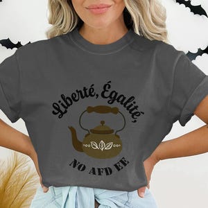 May include: A dark gray t-shirt with a graphic of a brown teapot and the text "Liberté, Égalité, No Afd Ee".