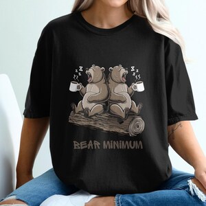 Puede incluir: Camiseta negra con un gráfico de dos osos bebiendo café y el texto "Bear Minimum".