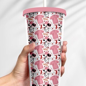 May include: A pink and white reusable tumbler with a straw. The tumbler has a pattern of medical symbols, including a stethoscope, a bandage, a syringe, and a blood pressure cuff.