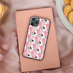 May include: A white iPhone case with a pink and red pattern of medical tools and scrubs. The case has a black border and a camera cutout.