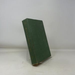 May include: A hardcover book with a green cover titled "Spoken and Written English" in gold lettering. The book is propped up on a clear plastic stand against a white background. The book's spine is visible.