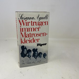 May include: A hardcover book titled "Wir trugen immer Matrosenkleider" by Susanna Agnelli. The cover features the title in red, the author's name, and a black and white photo of five children. The publisher's name, Piper, is also visible.