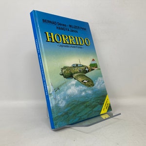 May include: A blue book titled "HORRIDO" with the text "Légcsatlik a Keleti Fronton" and the names "BERNAD Dénes", "MUJZER Péter", and "HANGYA János" on the cover. The book features an illustration of a green and white airplane flying over clouds.