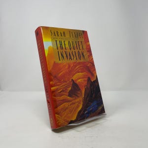 May include: A hardback book titled "The Quiet Invasion" by Sarah Zettel. The cover displays a landscape illustration in orange, red, and brown hues, with the title in gold lettering. The spine is red and includes the author's name and title.