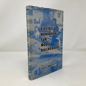 May include: A blue book titled "Electrical Handbook for Model Railroaders" by Paul Mallery. The cover features a photo of people working on a model railroad.