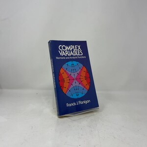 May include: A blue paperback book titled Complex Variables: Harmonic and Analytic Functions by Francis J. Flanigan. The cover features a circular graphic with a colorful, symmetrical pattern of intersecting curves and black directional arrows.
