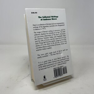 May include: A hardcover book titled "The Collected Writings of Ambrose Bierce" with a white cover and black text. The book includes quotes and a description of the author's work. The price is $48.95.