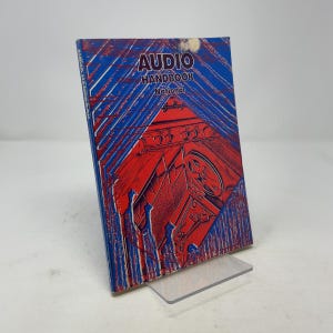 May include: A vintage "Audio Handbook" book with a red and blue cover. The cover features the title "AUDIO HANDBOOK" and the word "National". The book is displayed on a clear plastic stand.