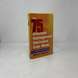 May include: A hardcover book titled The 75 Greatest Management Decisions Ever Made...and 21 of the worst by Stuart Crainer. The cover features a gradient orange and yellow background with large red text and a blue rectangular accent.