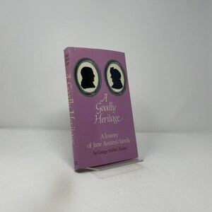 May include: A hardcover book titled "A Goodly Heritage" with a light purple cover. The cover features two black silhouettes in oval frames and the text "A history of Jane Austen's family".