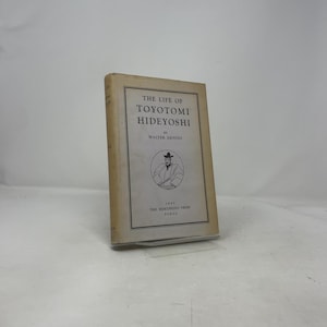 Puede incluir: Un libro antiguo titulado "The Life of Toyotomi Hideyoshi" de Walter Dening. La portada presenta un retrato de un hombre con vestimenta tradicional japonesa. El libro es de color blanquecino con texto negro y una pequeña ilustración. Publicado en Tokio.