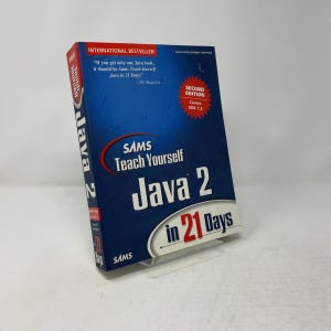 以下が含まれることがあります： Sams Teach Yourself Java 2 in 21 Days, Second Editionというタイトルの青いペーパーバックの技術書。表紙にはグリッドパターン、赤い星型のグラフィック、白い文字がデザインされています。背表紙にはタイトルとSamsのブランドロゴがはっきりと表示されています。