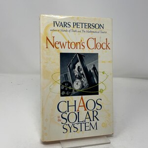 May include: A hardcover book titled Newton's Clock: Chaos in the Solar System by Ivars Peterson. The cover features a cream background with faint yellow celestial line drawings and a central black and white image of a mechanical clock mechanism.