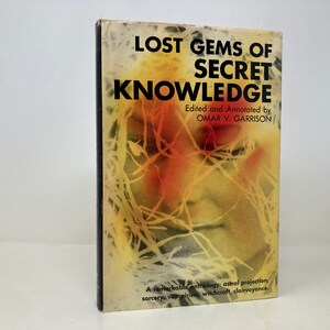 May include: A book titled "Lost Gems of Secret Knowledge" edited and annotated by Omar V. Garrison. The cover features a yellow, orange, and red abstract design with a face obscured by lines.