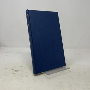 May include: A dark blue hardcover book with a textured fabric cover. The spine features gold lettering that reads The Printed Writings of Jonathan Edwards and the publisher name Burt Franklin. The book is displayed upright on a clear stand.