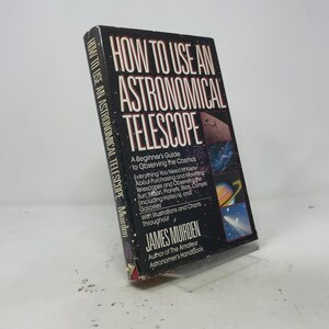 May include: A hardcover book titled How to Use an Astronomical Telescope by James Muirden. The black cover features white text, a starfield background, and four small square images showing the moon, a nebula, Saturn, and a comet in space.