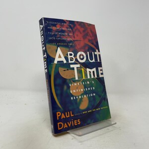 May include: A paperback book titled About Time: Einstein's Unfinished Revolution by Paul Davies. The cover features a dark blue background with abstract yellow and orange circular shapes, white text, and a quote from the Los Angeles Times.