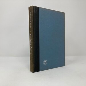 Può includere: Un libro rilegato in marrone con una costa blu e il titolo "Testing Time" di Harrison Smith. Il libro ha una costa nera con un emblema dorato.